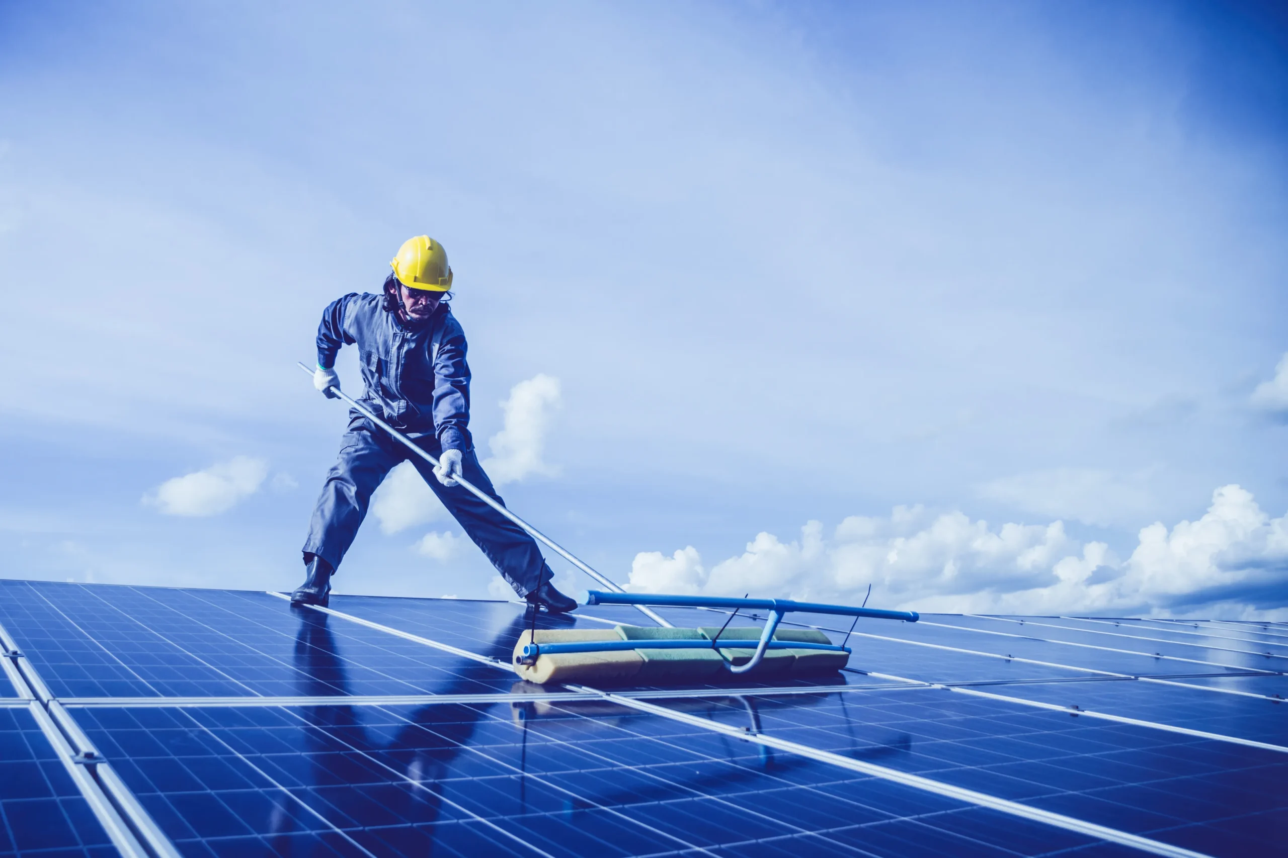Professional solar panel cleaning service with a technician cleaning rooftop solar panels