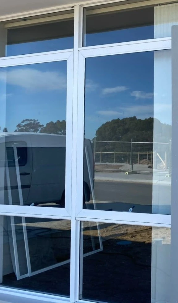 Clean exterior windows reflecting blue sky and surrounding trees after window cleaning services